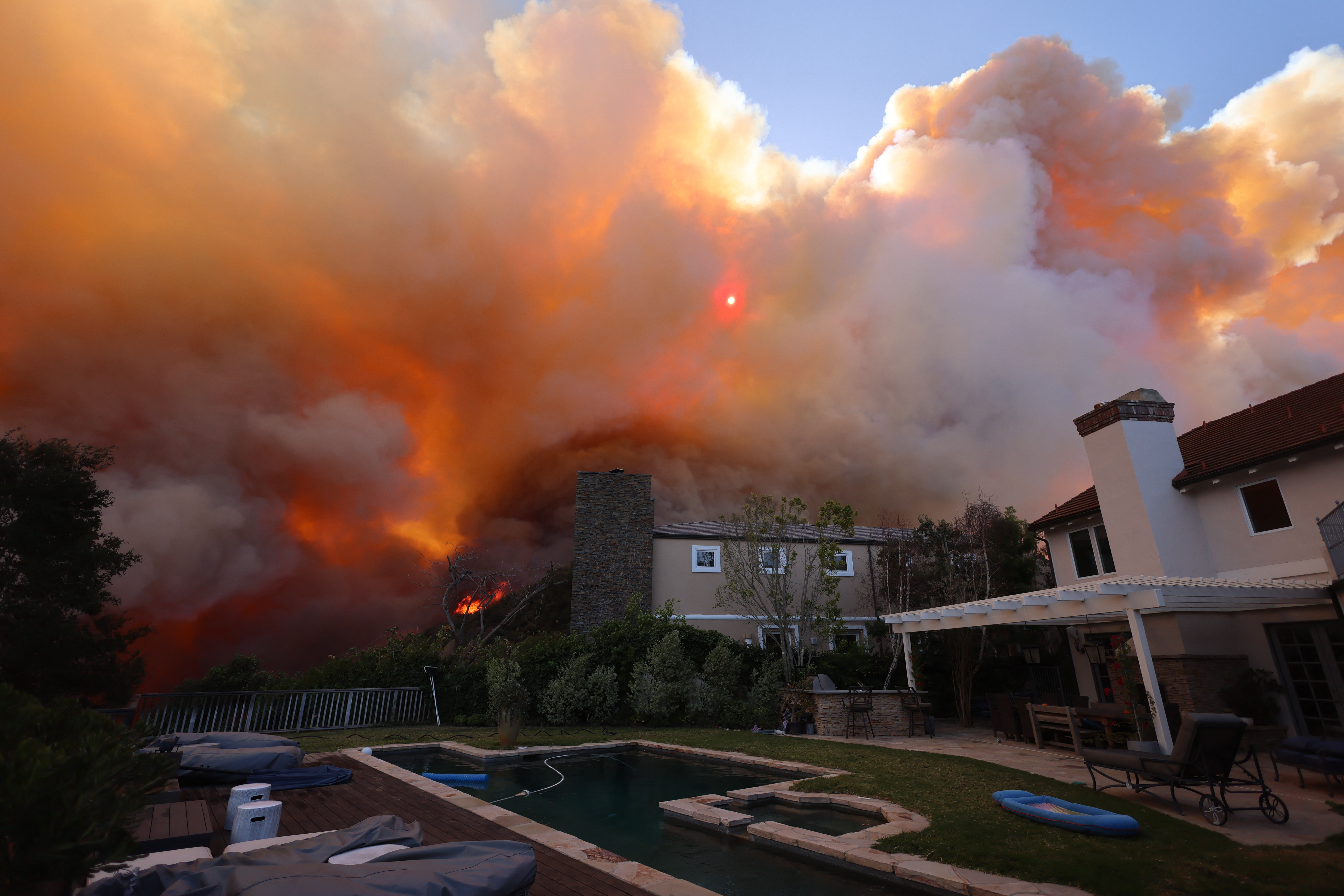 A brush fire burns near homes in Pacific Palisades, California on January 7, 2025. (Photo by David Swanson / AFP) (Photo by DAVID SWANSON/AFP via Getty Images)