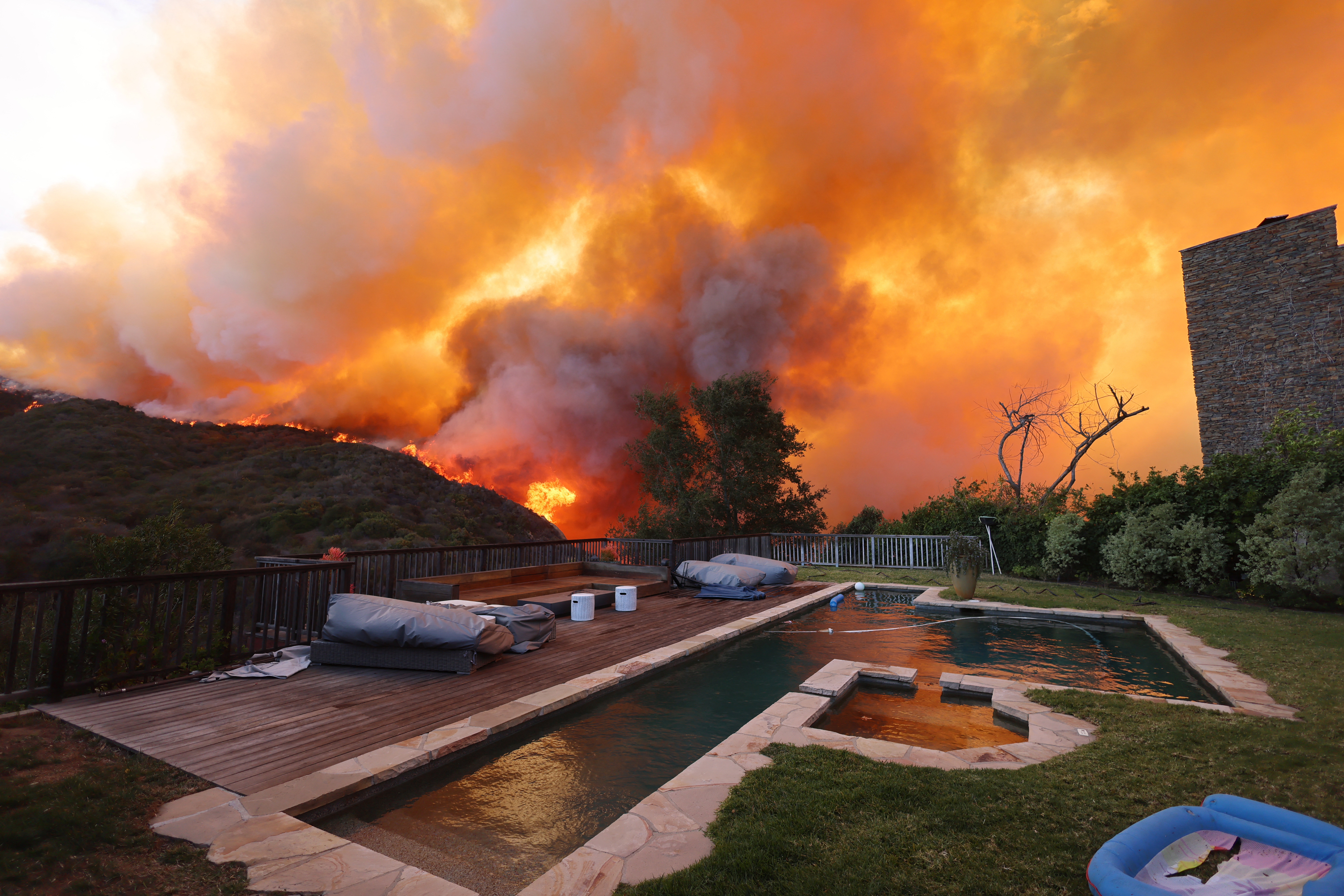 TOPSHOT – A brush fire burns near homes in Pacific Palisades, California on January 7, 2025.  (Photo by David Swanson / AFP) (Photo by DAVID SWANSON/AFP via Getty Images)