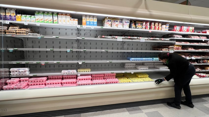 A grocery store worker rearranges items in the depleted egg section