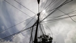 FILE – A utility pole with loose cables towers over a home in Loiza, Puerto Rico, Sept. 15, 2022. (AP Photo/Alejandro Granadillo, File)