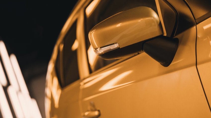 Night image of bronze-colored car reflecting street lights at night.