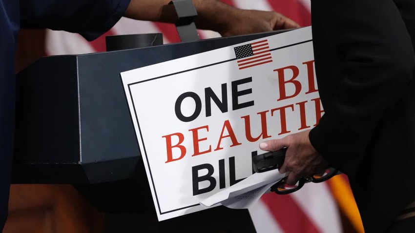 Staff members remove a sign following a press conference after the House passage of the tax and spending bill, at the U.S. Capitol on May 22, 2025 in Washington, DC.