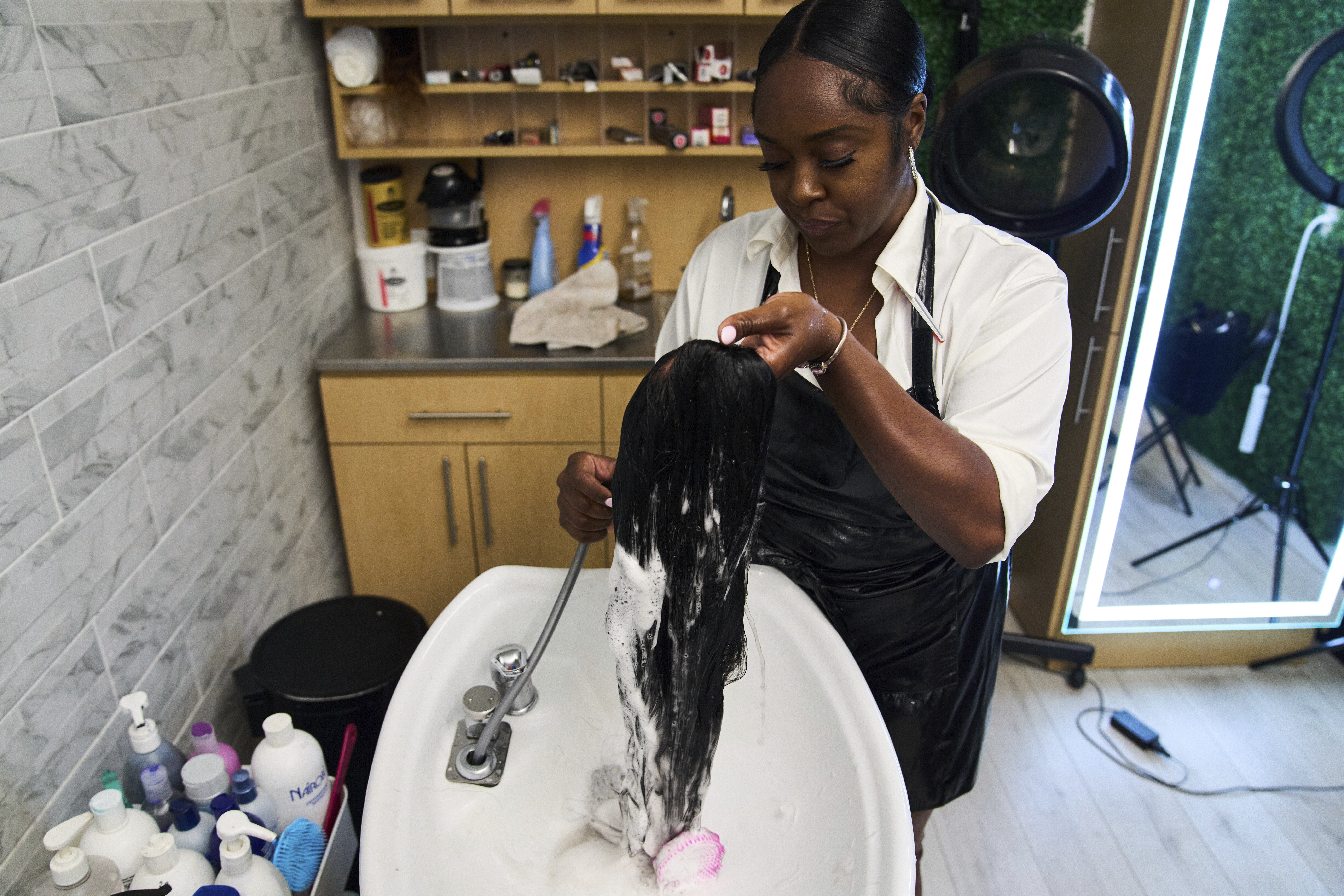 Dajiah Blackshear, a natural hair stylist who specializes in extensions, washes a client's wig during an installation service, Monday, May 5, 2025, at her salon suite in Atlanta. (AP Photo/Stephanie Scarbrough)