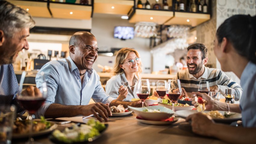 Cheerful business colleagues talking about something funny on a lunch break in a restaurant.