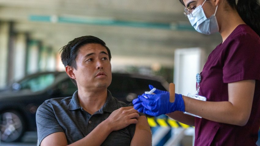 Pasadena, CA – October 12: Justine Castillo Martinez, LVN, right, takes a moment to show her patient Phillip Soon, 38, the syringe during a flu and COVID-19 vaccination clinic at Kaiser Permanente Pasadena on Thursday, Oct. 12, 2023, in Pasadena, CA. Soon was getting both the flu and COVID-19 vaccination.