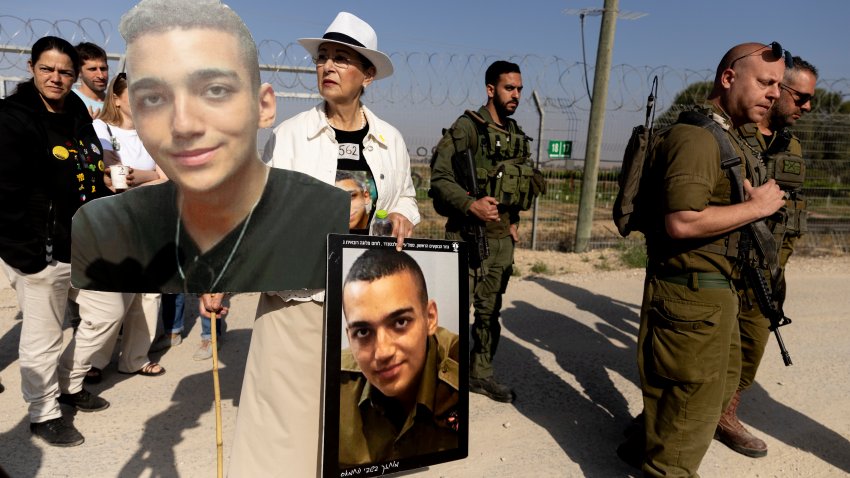 NIR OZ, ISRAEL – APRIL 20: Varda Ben Baruch holds photos of her grandson Israeli- American hostage Edan Alexander as she walks near Israeli soldiers during a rally of families of hostages held in the Gaza Strip at Nir Oz near the border with the Gaza Strip on April 20, 2025 in Nir Oz, Israel.