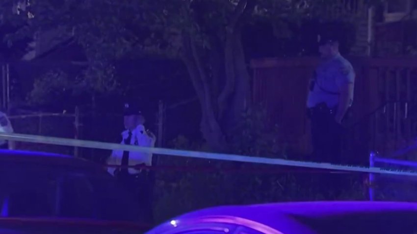 Police officers behind police tape at night.
