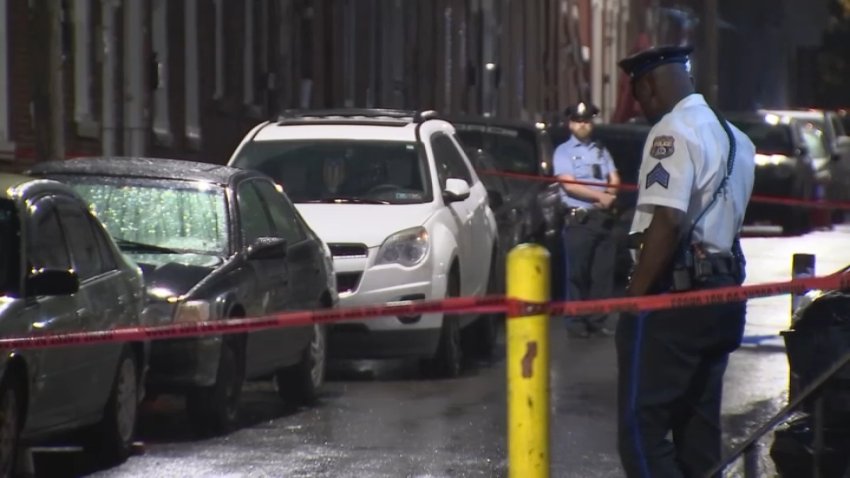 Red crime scene tape blocks off where a man was shot and killed in North Philadelphia as police investigate.