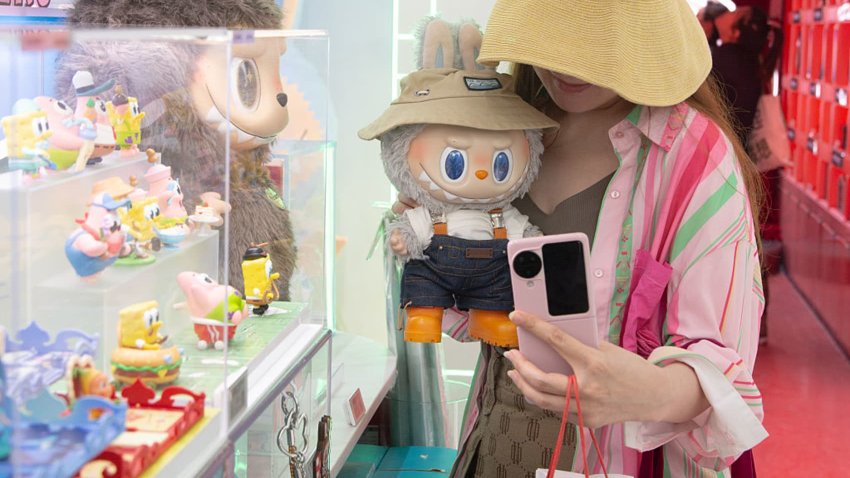 A woman takes pictures with a Labubu doll at a Pop Mart store in Shanghai, China, on June 5, 2025.