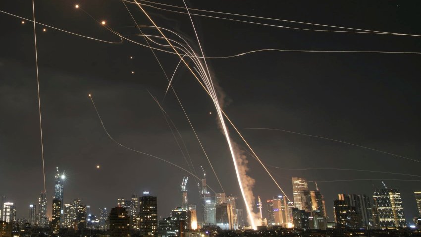 A projectile hit buildings as Israeli Iron Dome air defense system fires to intercept missiles over Tel Aviv, Israel, Friday, June 13, 2025.