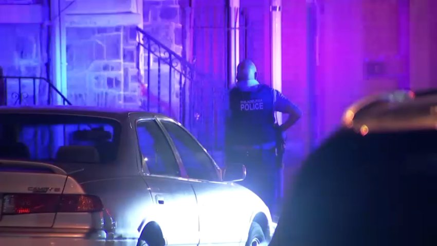 A Philadelphia police officer inspects the scene after a man was shot along Cemetery Ave. in Southwest Philly early Sunday.