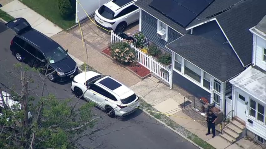 An officer stands outside a home in Hamilton Township, NJ, where officials believe a man killed his girlfriend and her 10-year-old daughter before taking his own life early Thursday.