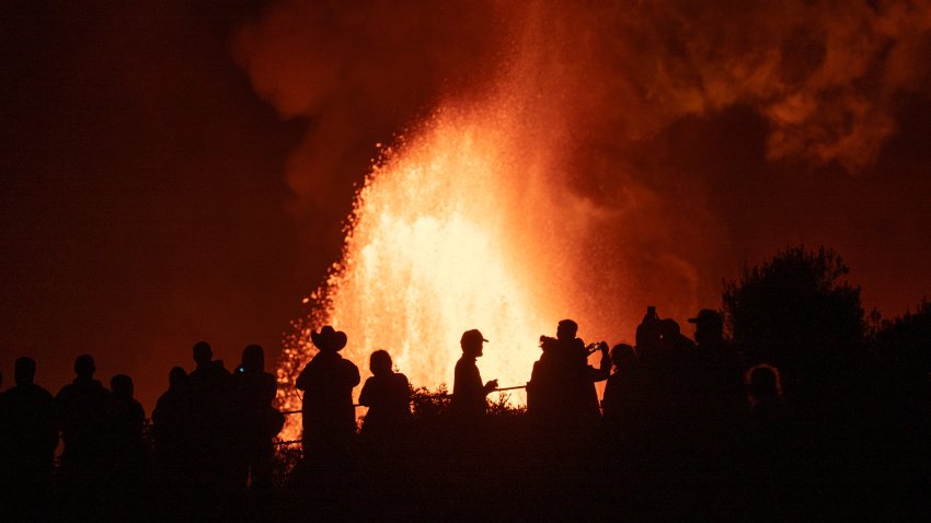 Silhouettes of people standing in front of volcano
