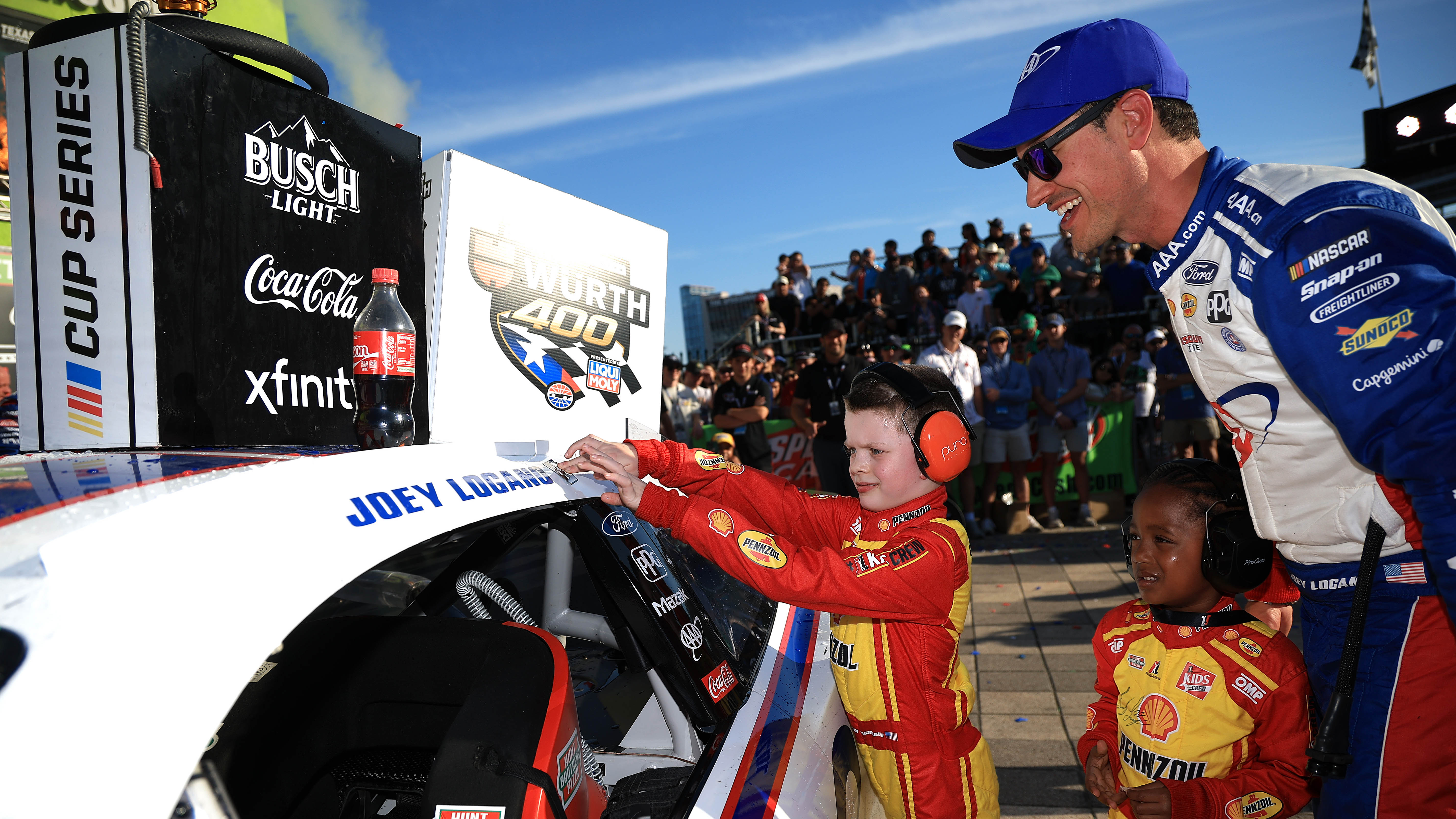 Joey Logano, driver of the No. 22 Ford, has a guest from the JL Kids Crew place the winner sticker on his car in victory lane
