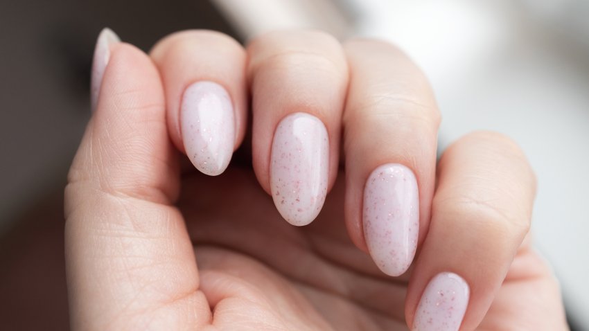 Close-up of woman’s hand with elegant pale pink manicured nails, showcasing subtle and stylish look. Nail care concept