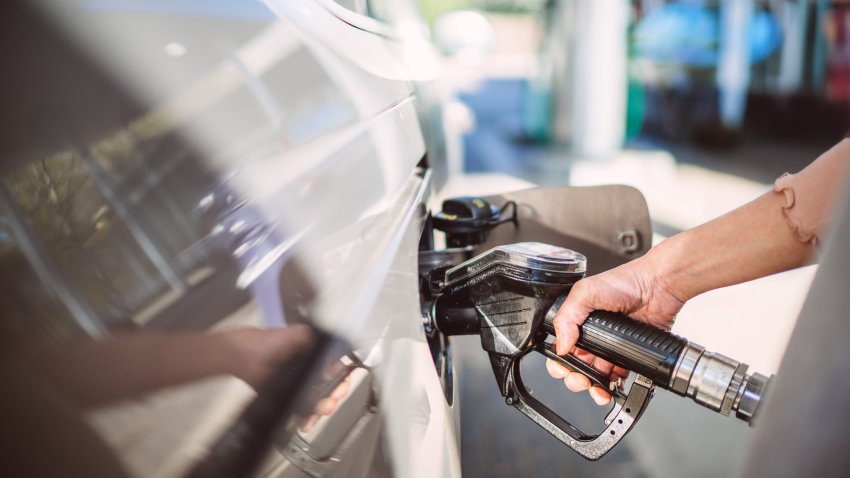 Close-up of a woman’s hand holding a diesel fuel pump while refueling a car at a gas station