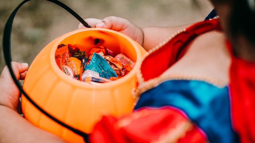 Baby girl holding candies in pumpkin basket